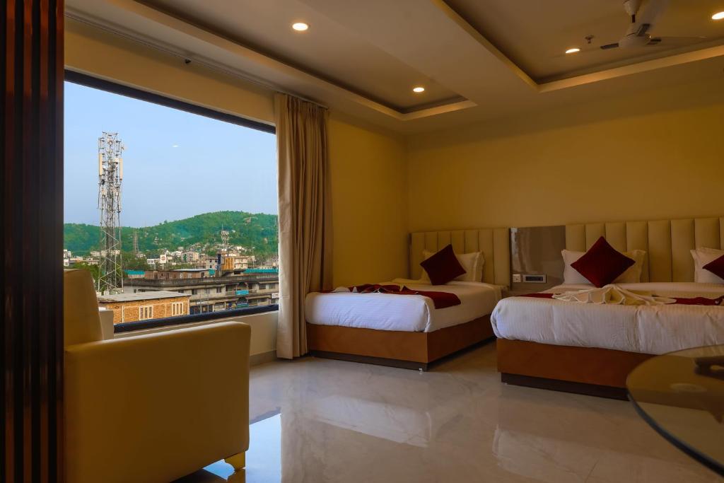 a hotel room with two beds and a large window at Briddhishree Palace in Guwahati