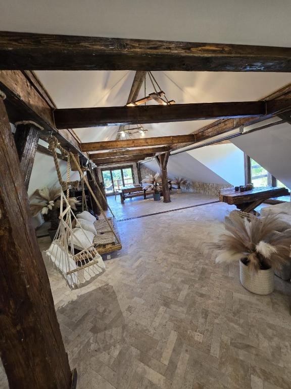 an attic room with wooden beams and a table at Apartament-SŁOVIAŃSKI ZAKĄTEK in Nowakowo