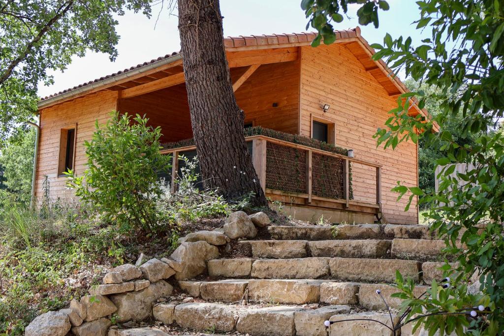 a house with stairs in front of a tree at Chalet tous confort avec piscine lagon in Vallon-Pont-dʼArc