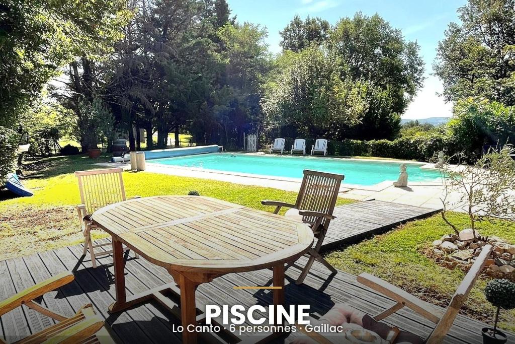 a wooden table and chairs next to a swimming pool at Lo Canto in Gaillac
