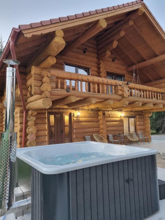 a large hot tub in front of a log cabin at Cabana dintre brazi Mărișel in Dealu Negru