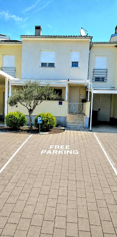 a white building with a tree in a parking lot at Rooms Hana Rovinj in Rovinj
