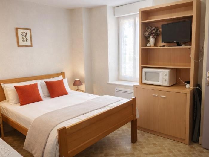 a bedroom with a bed and a tv on a shelf at Aux Coquelicots in Saint-Honoré-les-Bains