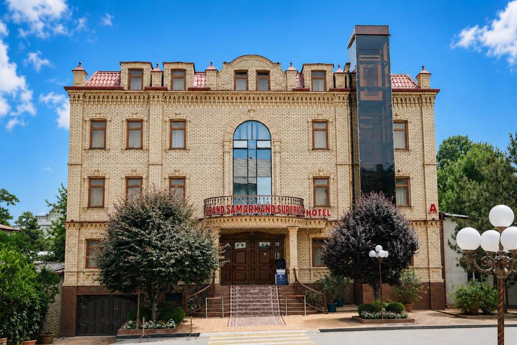 a large brick building with a clock tower on top at Hotel Grand Samarkand Superior - A in Samarkand