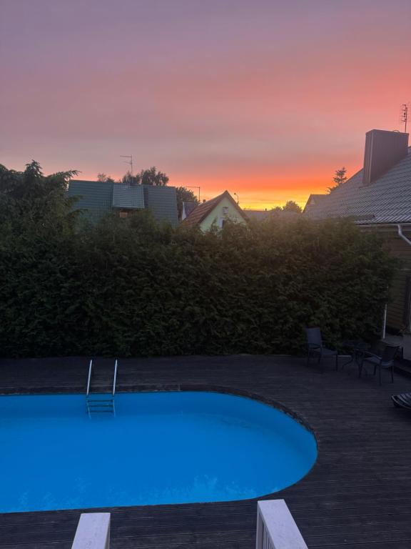 a blue swimming pool with a sunset in the background at Saules namu kambariukas in Palanga