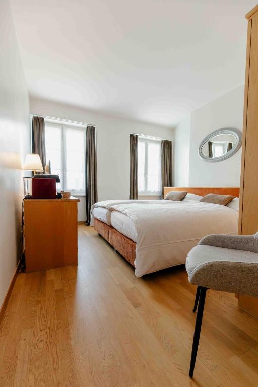 a large bedroom with two beds and a chair at Hôtel du Cheval Blanc - City center in Bulle