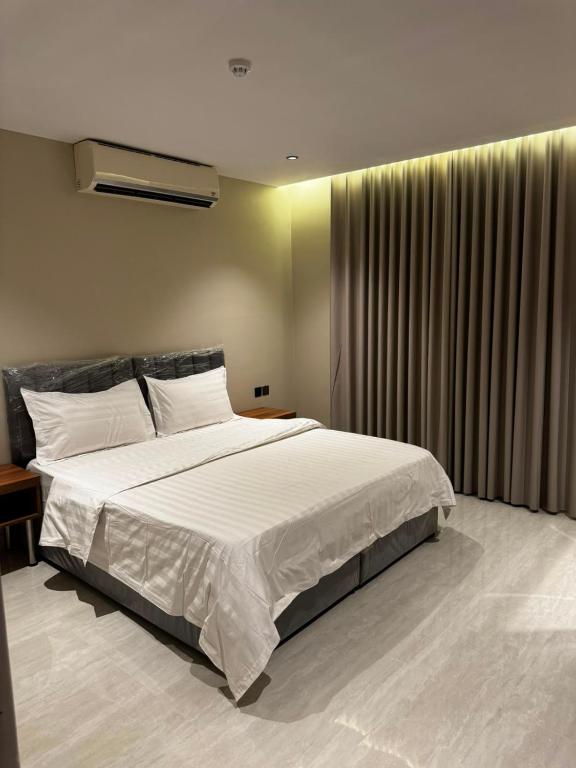 a bedroom with a large bed with white sheets at الشهداء الفاخر للشقق المخدومة in Medina