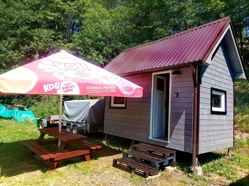a small house with a picnic table and an umbrella at Chata na kolech 4L v areálu Koupaliště Bystré v Orlických horách in Bystré
