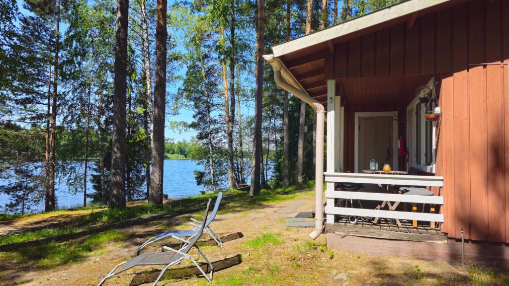 a building with a chair next to a lake at Koivurannan Lomamökit Paju in Mikkeli