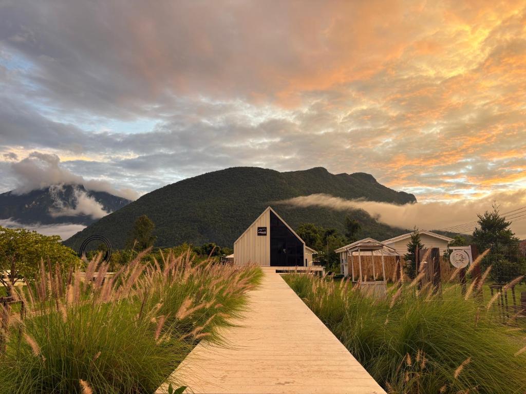 a wooden path leading to a barn and a mountain at Paradise Resort & Cafe in Ban Mae Khon