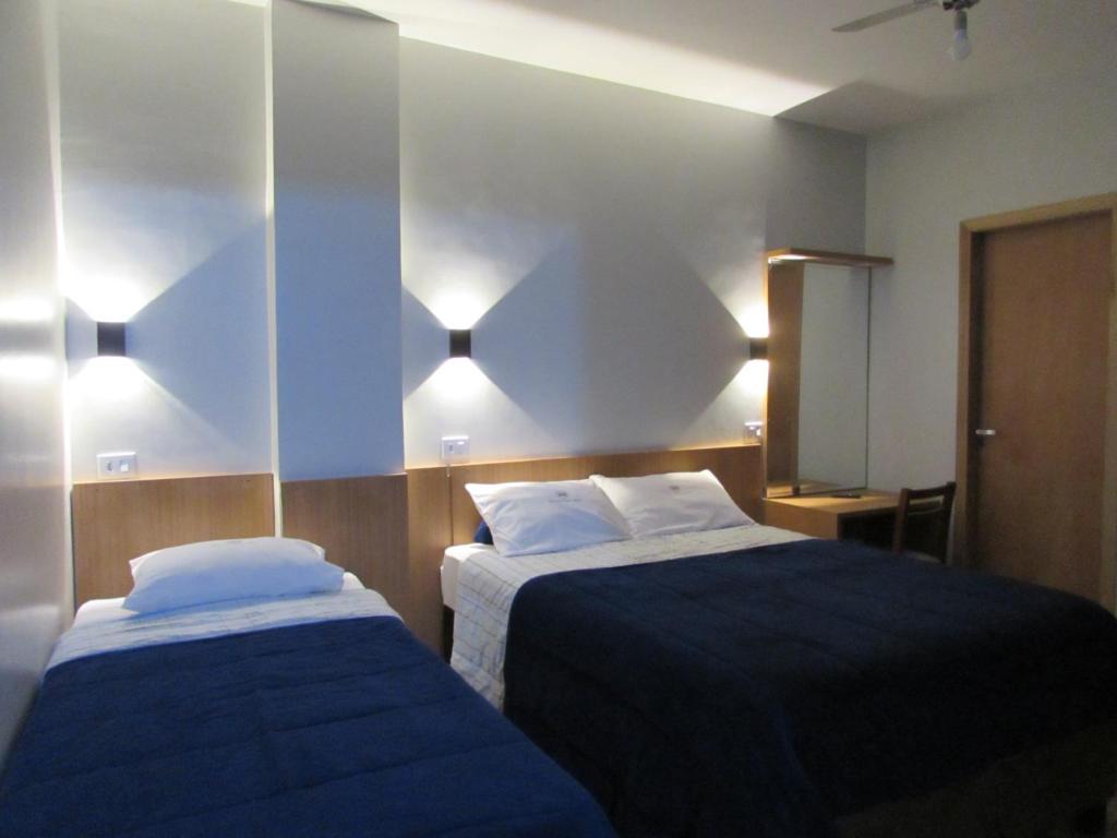 a bedroom with two beds and a mirror at New Comercial Palace Hotel in São Paulo