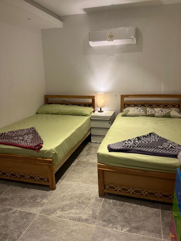 two beds in a bedroom with a lamp on a table at Krir city villa in Alexandria