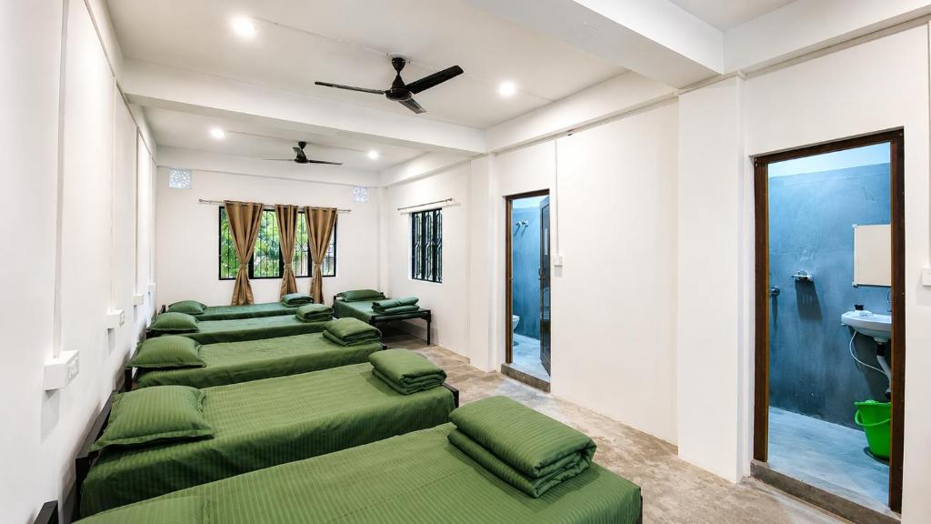 a row of green beds in a room at Goshen dormitory in Siliguri