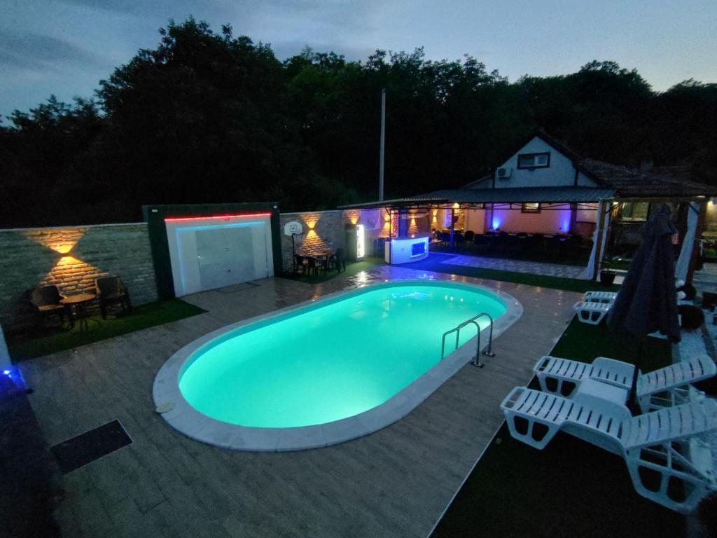 a swimming pool in a backyard at night at Vikend house Cvrcak in Slankamenački Vinogradi