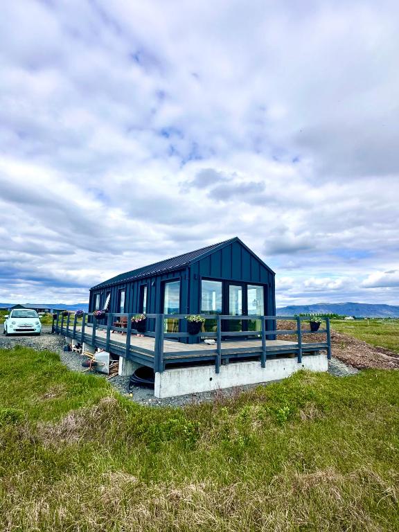 a blue building with a car parked in a field at Bárucottage in Eyrarbakki
