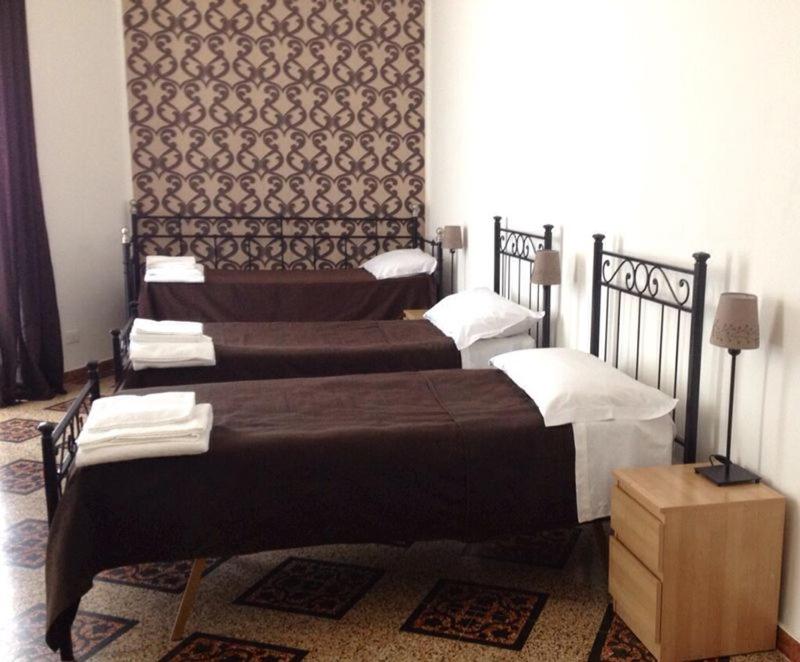 two large beds in a room with a wall at Hostel Castello Maggiore in Rome