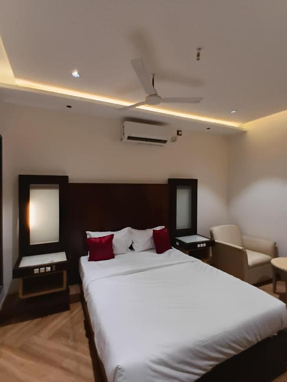 a bedroom with a large white bed with red pillows at hotel sunfire in Chhindwāra
