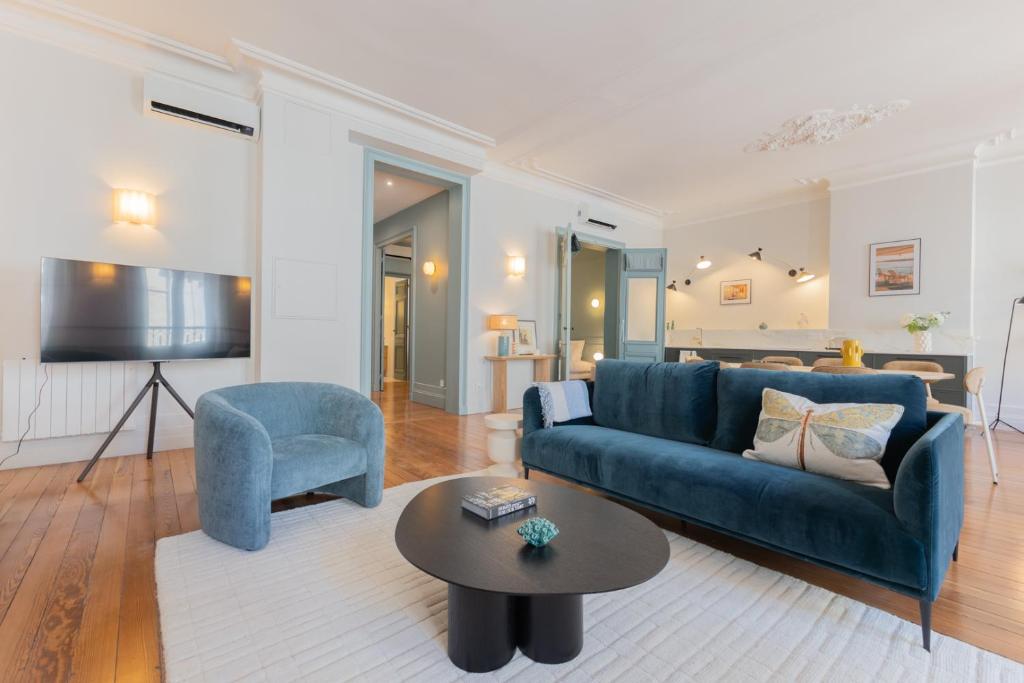 a living room with a blue couch and a table at Luxueux Appartement - Hyper Centre - Climatisation - Balcon in Bordeaux