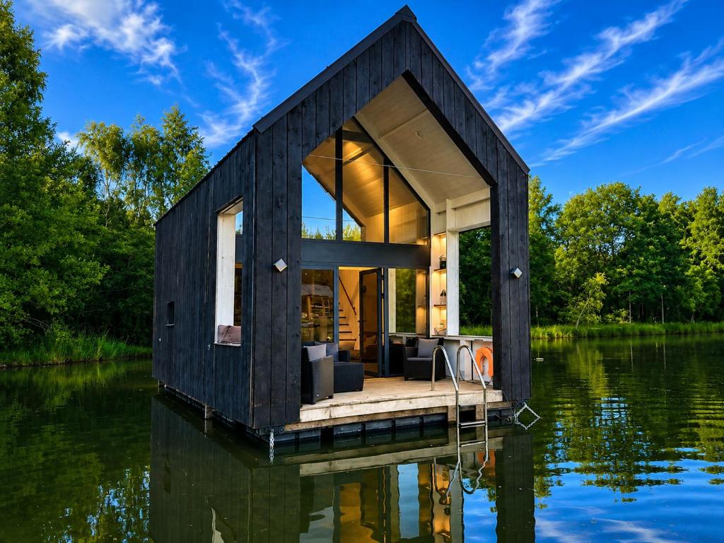 a black tiny house on a body of water at Les Kabanes de Kerforn in Crach