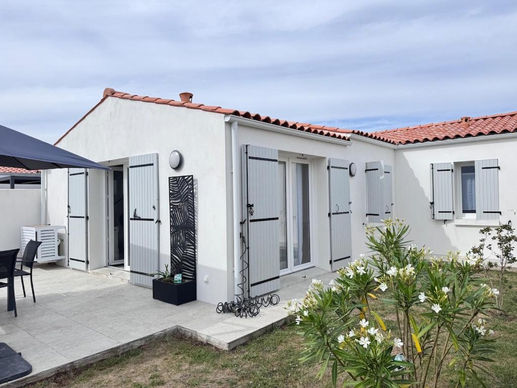 a white house with a patio and a table at Ideal pour un couple in Saint-Georges-dʼOléron
