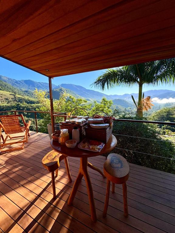 a table on a deck with a view of the mountains at Pousada Varandas da Mantiqueira in São Francisco Xavier