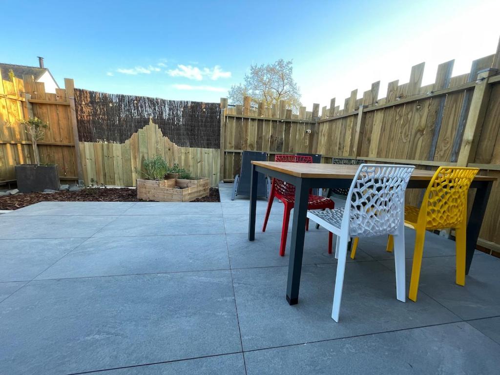 a table and chairs on a patio with a fence at L échappée bêle in Le Val-Saint-Père
