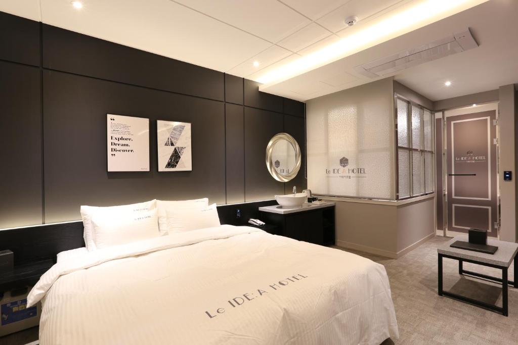 a bedroom with a large white bed and a sink at Le Idea Hotel Busan Station in Busan