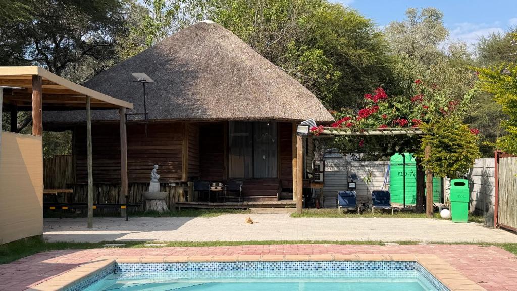a house with a thatch roof and a swimming pool at Ghxabara Cozy Cabin in Maun