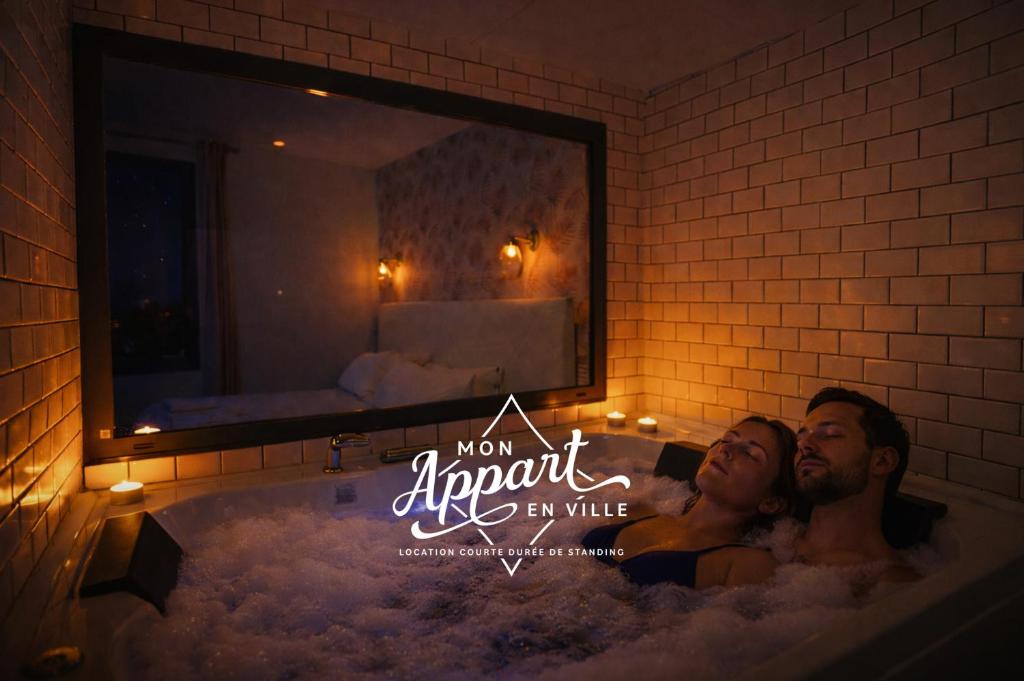 a man and woman in a bathtub with a mirror at Le Maleville - Appartements de Standing in Périgueux