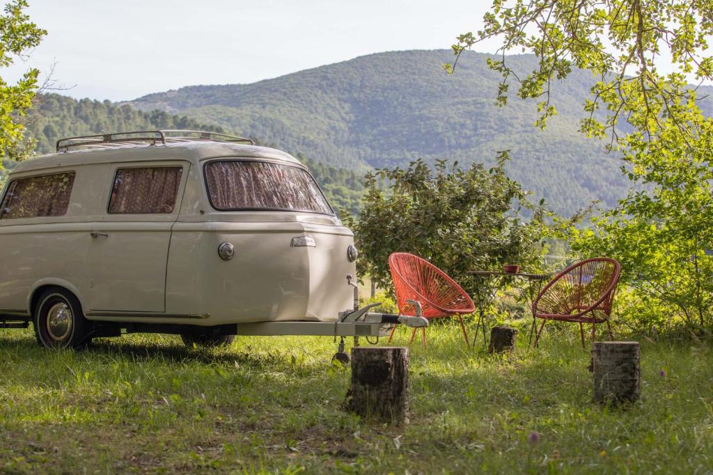 an old van parked in a field with two chairs at La Permaculturelle - Domaine des Ramières in Le Poët-Laval