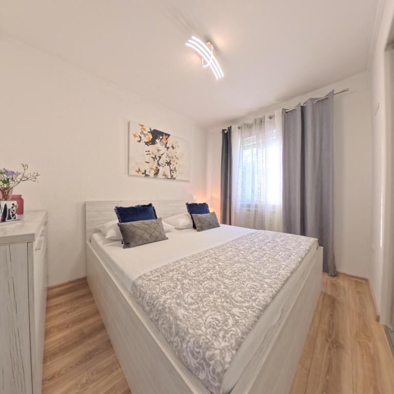 a white bedroom with a large white bed with blue pillows at CASA di NATALIA, Spacious 2BR Apartment for 6 near Beach ,Free Parking in Kaštela