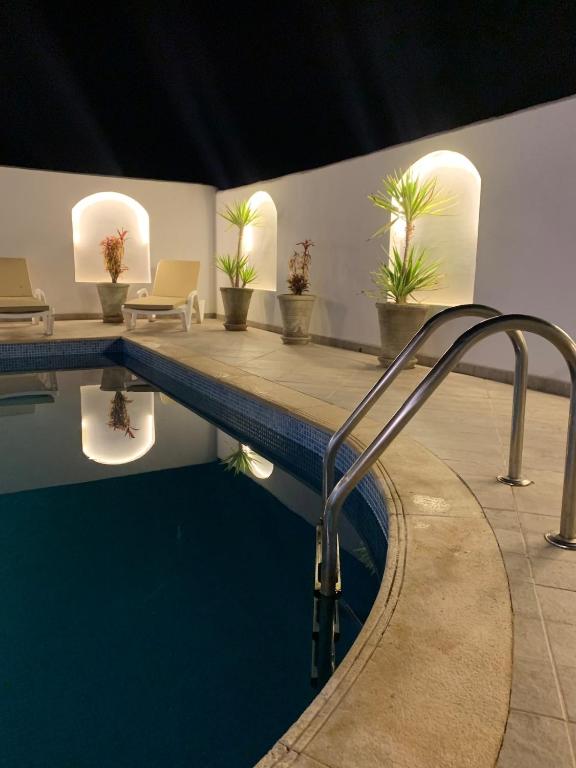 a swimming pool with a metal railing next to a swimming pool at Villa Syrine Djerba in Al Ḩaddādah