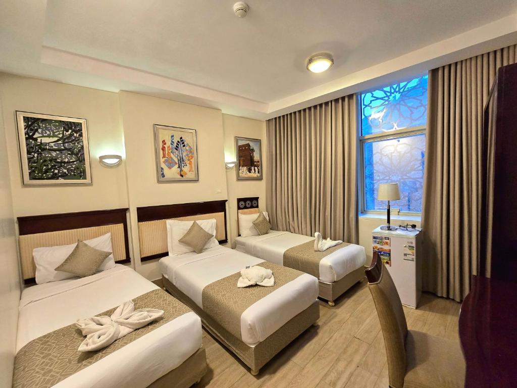 a hotel room with two beds and a window at Midhal Al Ezz Ajyad Hotelفندق مدهال العز in Mecca