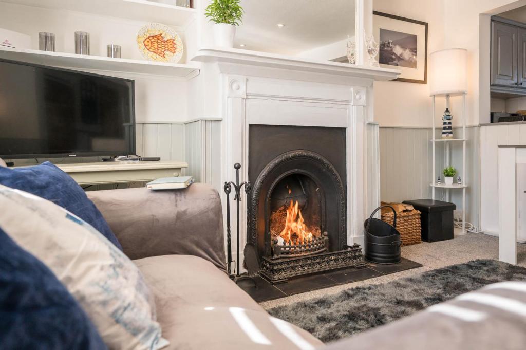 a living room with a fireplace and a couch at Fishermans Cottage, Aldeburgh in Aldeburgh