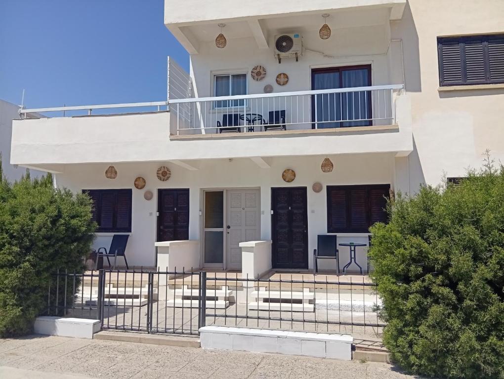 a white house with a balcony and chairs at Sea Apartments in Larnaca