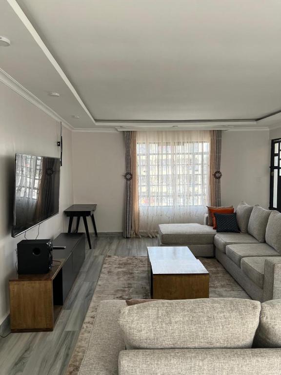 a living room with a couch and a flat screen tv at Noble Park Apartment in Kiserian