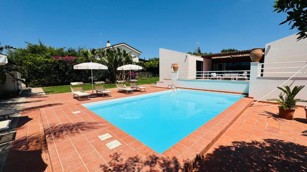 a swimming pool in a yard with chairs and umbrellas at Villa Bruno in Modica