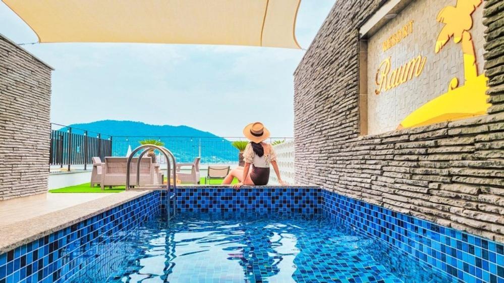 a woman in a hat standing next to a swimming pool at Raum Resort 1 in Suncheon