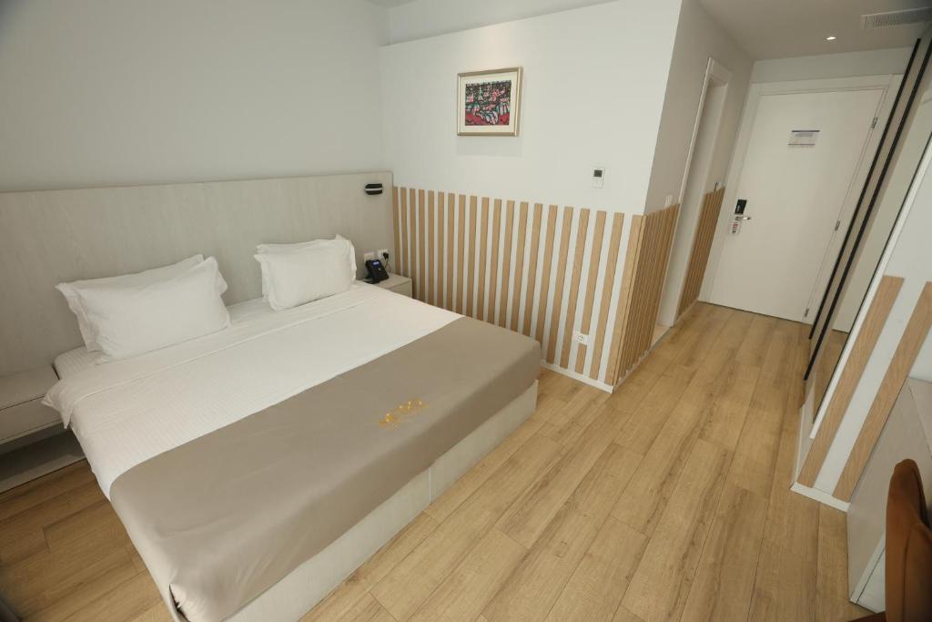 a bedroom with a white bed and a wooden floor at Metro Hotel Terminal in Tirana