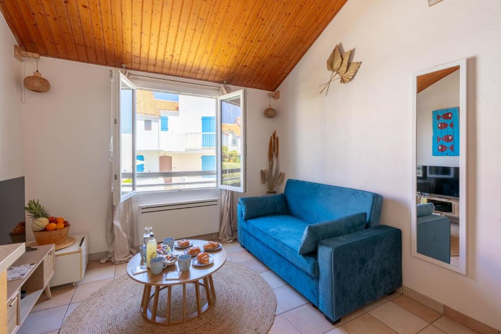 a living room with a blue couch and a table at Le Refuge des Embruns - Port & plages - 4 pers - Tout confort et équipé in LʼHerbaudière
