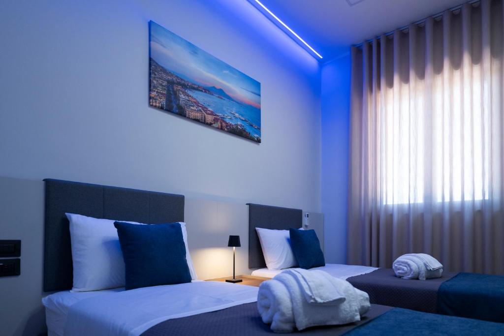 a blue room with two beds and a window at 3 torri GATEWAY in Maddaloni