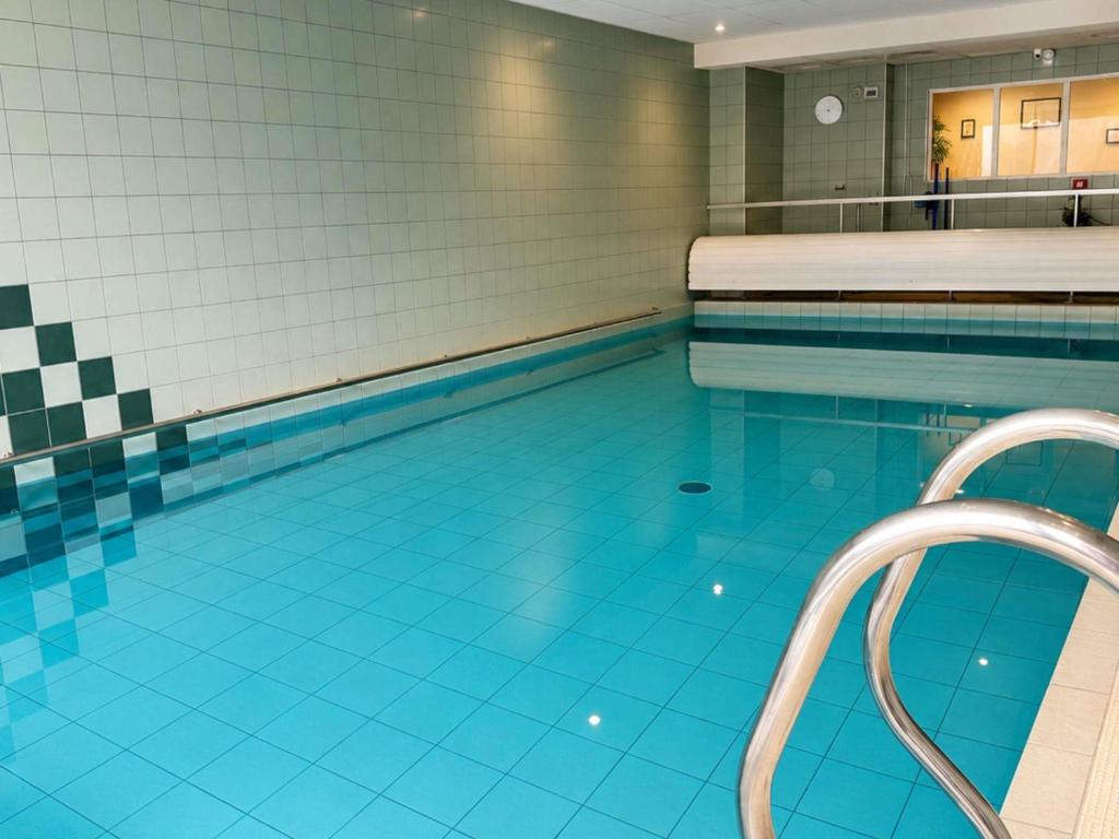 a swimming pool with blue tiles on the floor at ibis Styles Clermont Ferrand Sud La Pardieu in Clermont-Ferrand