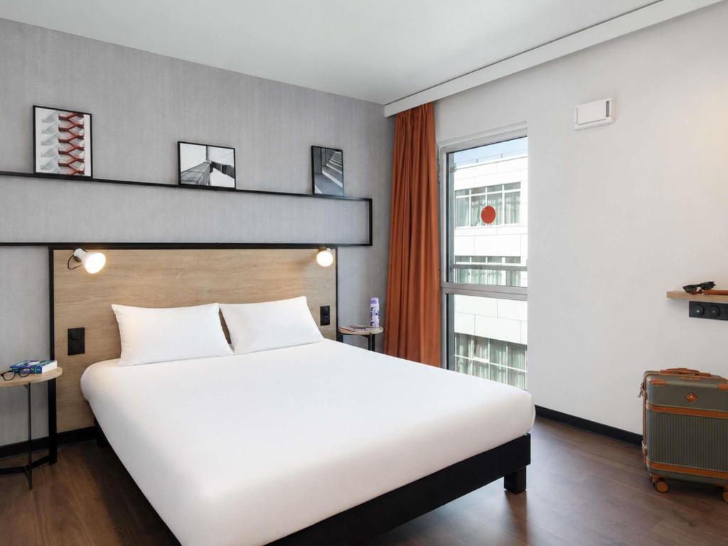 a bedroom with a large white bed and a window at Ibis Clermont-Ferrand Centre Stade in Clermont-Ferrand