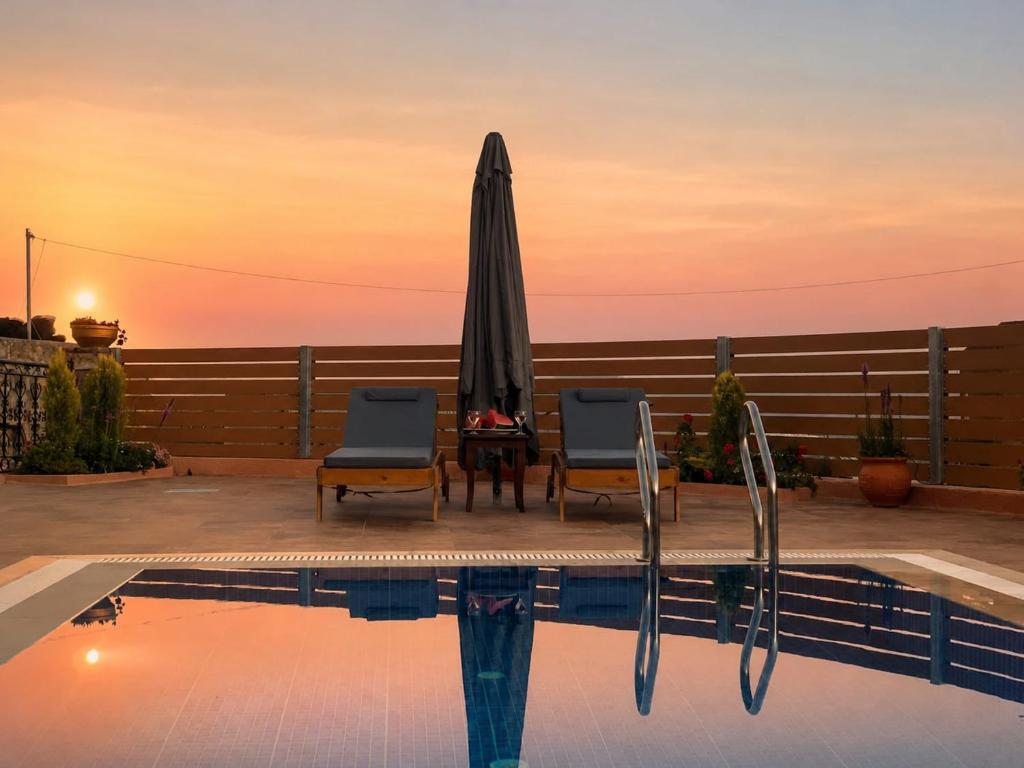 a swimming pool with two chairs and an umbrella at Villa Maria Christina with Private Pool in Crete in Skoúrvoula