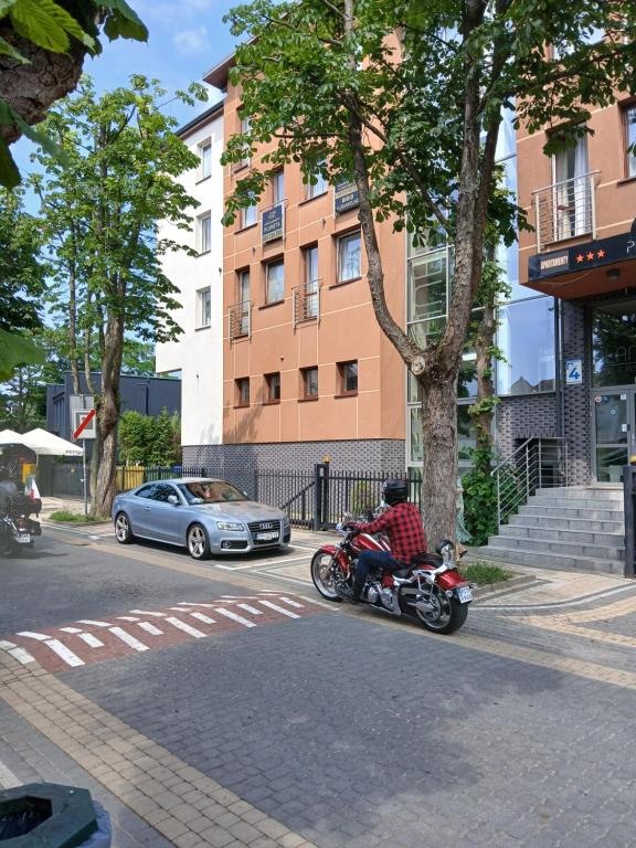 a man riding a motorcycle down the street at Apartament 112 Mielno in Mielno