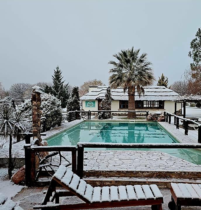a swimming pool covered in snow in front of a house at Cabañas Altos de la Bodega in San Rafael