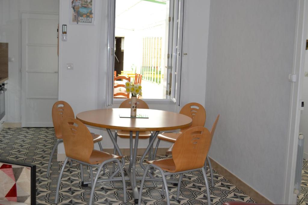 a dining room with a table and four chairs at Gîte les Grands Orangers in Melle