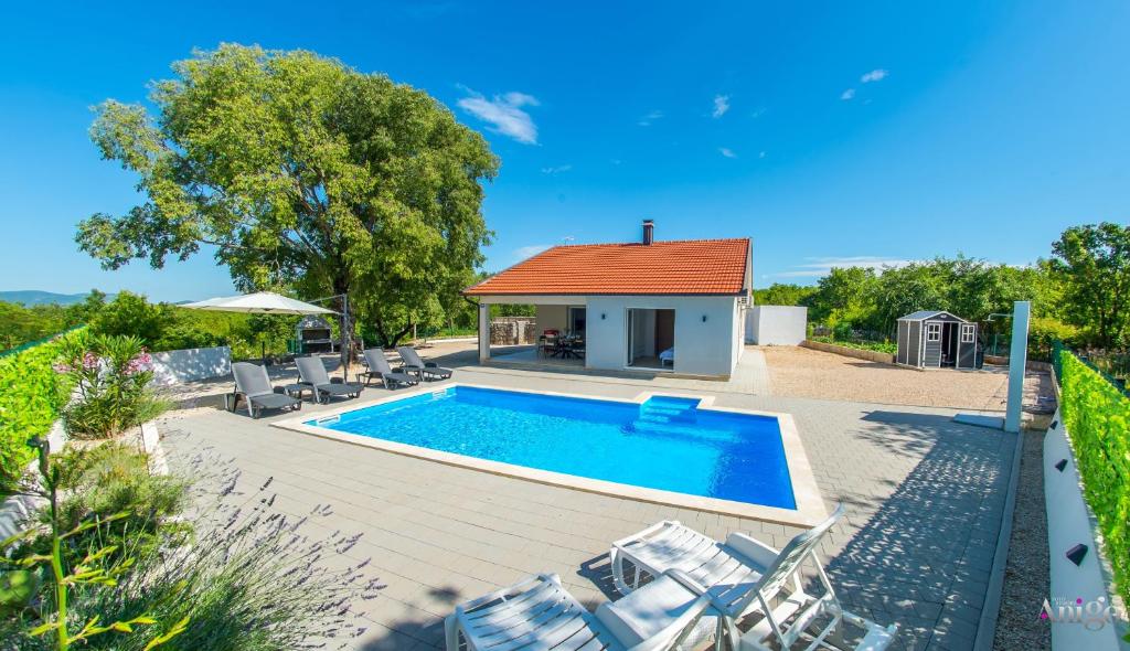 a swimming pool with chairs and a house at Kuća za odmor Veronika in Klobuk