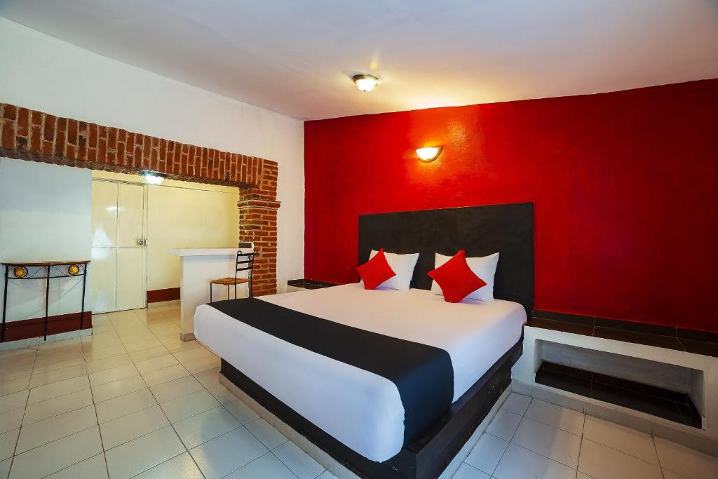 a bedroom with a large bed with a red wall at Capital O Hotel Meson Del Rio, Tepotzotlan in Tepotzotlán