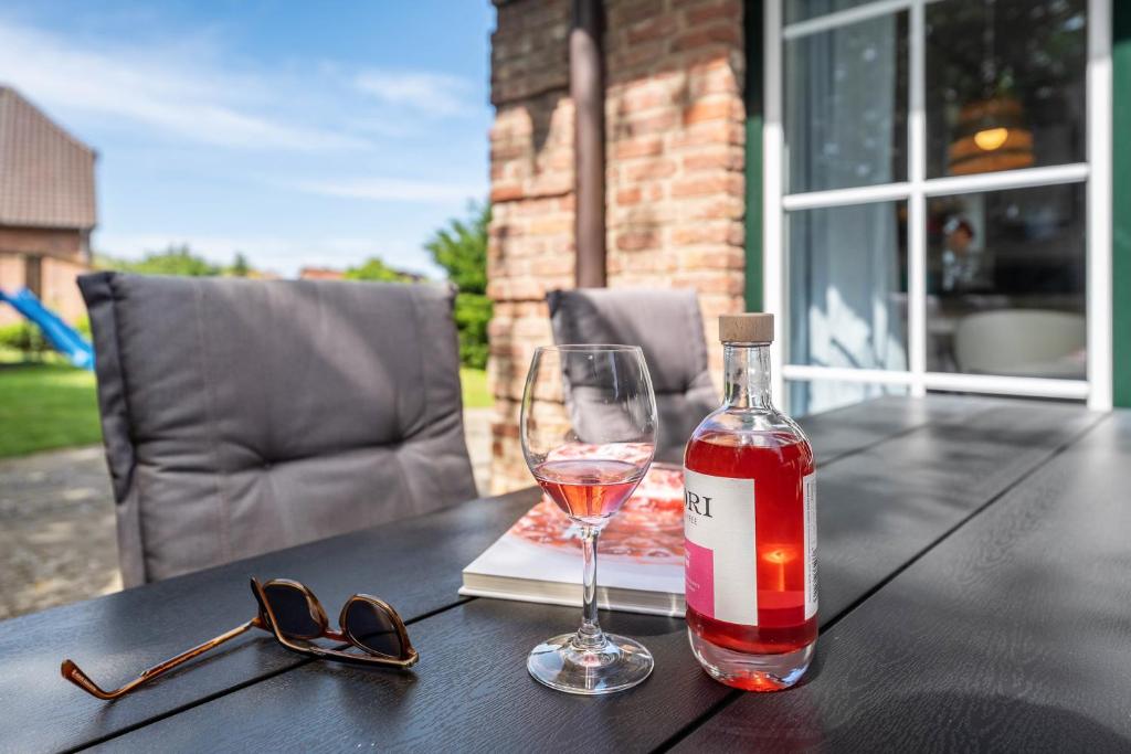 a bottle of wine and a glass on a table at Haus Am Dorfteich B eingefriedet in Fehmarn